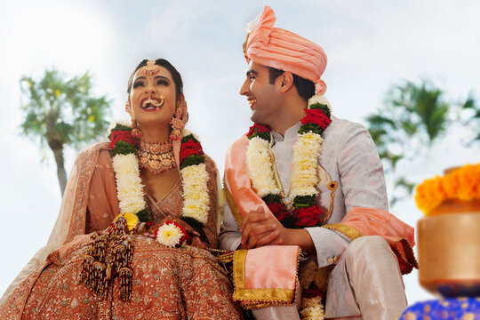 Happy bride and groom sitting together at wedding mandap