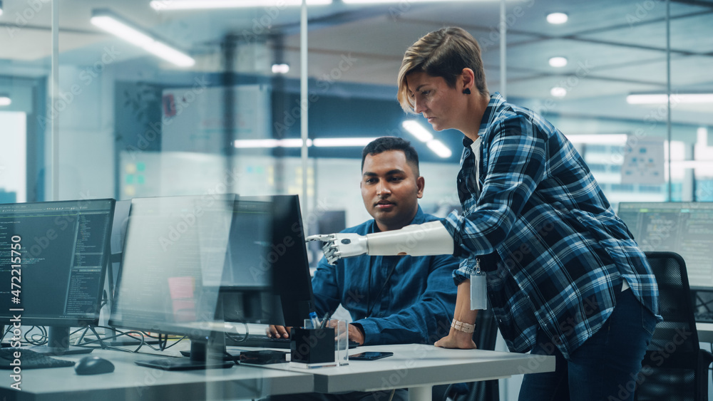 Poster Teamwork In Diverse Inclusive Office: Woman with Disability Project Manager with Prosthetic Arm Talks with Indian Specialist Working on Desktop Computer. Professionals Software Engineers Create App