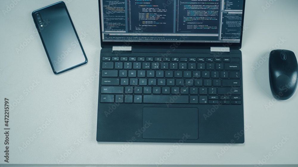 Poster Top Down View of Laptop Computer with Developers Code on Screen, Smartphone with Rare Cameras and Computer Mouse on the Left. Professionals Software Engineers Create App on Laptop