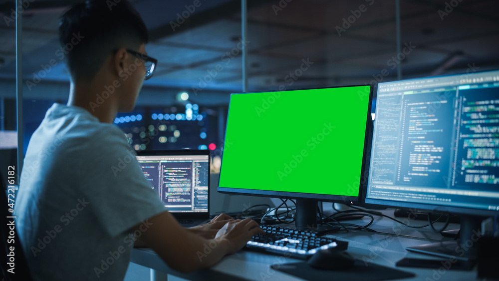 Poster Night Office: Young Japanese Man in Working on Green Screen Chroma Key Desktop Computer. Team of Programmers Typing Code, Creating Modern Software, e-Commerce App Design, e-Business Programming