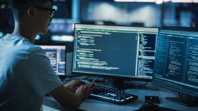 Night Office: Young Handsome Man in Working on Desktop Computer. Digital Entrepreneur Typing Code, Developing Modern Software, e-Commerce App Design, Developing of e-Business. Over Shoulder