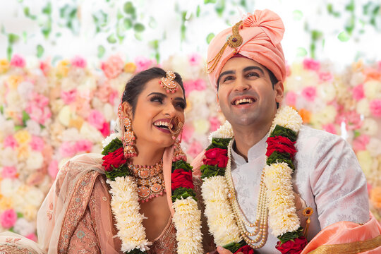Portrait of a happy Indian wedding couple sitting together on mandap