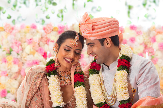 Portrait of a happy Indian wedding couple sitting together on mandap