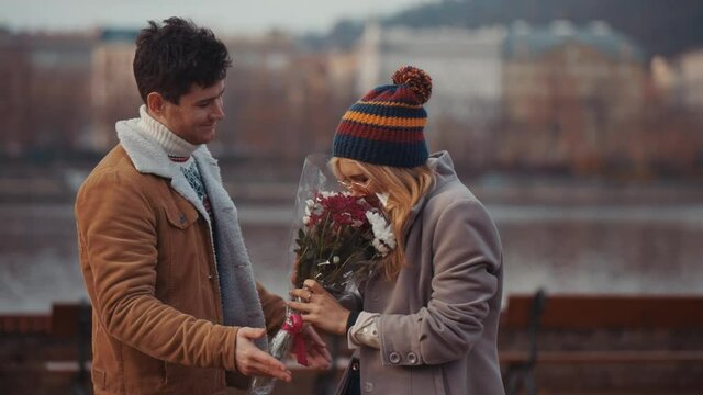 Young man giving bloom flower bouquet to woman on Valentine day, first date. Valentine day concept, love and funny advertizing