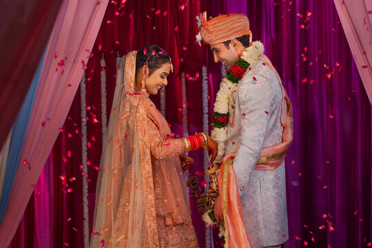 Portrait of a couple in traditional wedding outfit standing at mandap during Jaimala 