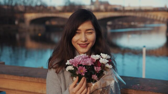 portrait of a young asian women, bribes with flowers, smiling at the camera. against the background of a European city with a river. Czech Republic. England London. Full Bloom