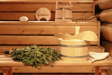 Birch broom on a wooden bench and traditional sauna accessories in the interior of the Russian...