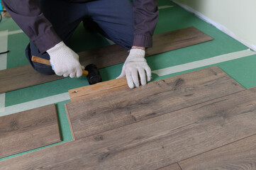 The master is laying the laminate. The man is doing the repair of the floor. 