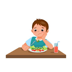 Cute little boy picky eater frustrating looking at broccoli with no appetite and refusing to eat vegetables.

 - obrazy, fototapety, plakaty