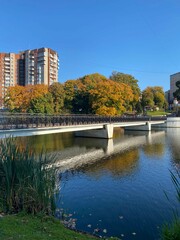 Obraz premium Breathtaking view to The Lower Pond and a park near it in Kaliningrad city in Russia in the golden autumn season. Colorful trees and clouds reflect in the lake waters