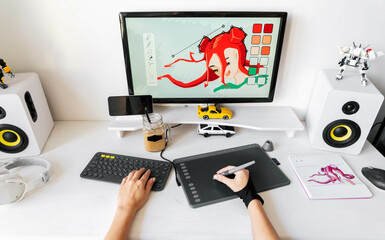 A young girl profession digital artist draws on a PC using a graphics tablet in her comfortable...