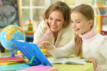 Cute girl with her mother doing homework