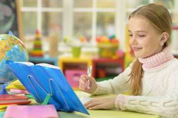 Cute girl leaning on hand while doing her homework