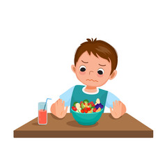 Little boy picky eater refusing to eat showing hand pushing at bowl of fruits and vegetables.

