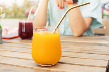 A woman in a street cafe or on the terrace of her house drinks a delicious smoothie cocktail