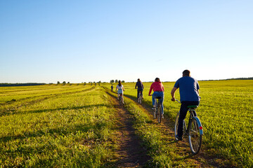 Obraz premium Cyclist on a dirt land road in a field at a summer day or evening