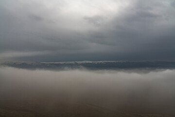 Beautiful winter landscape. The huge clouds above the mountains. Foggy weather