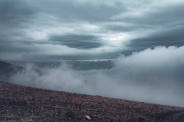 Beautiful winter landscape. The huge clouds above the mountains. Foggy weather
