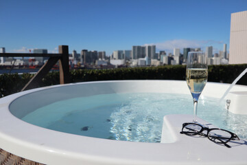 都会の街並みを望む露天風呂とシャンパングラス outdoor bath and a champagne...