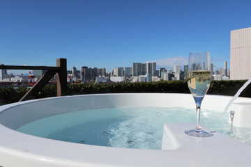 都会の街並みを望む露天風呂とシャンパングラス outdoor bath and a champagne glass 