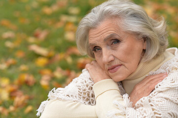 Close up portrait of sad senior woman in autumn park