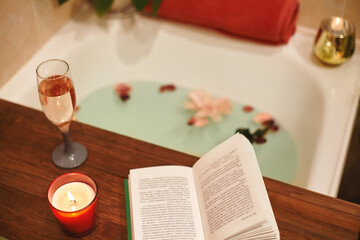 Naklejka na ściany i meble Bath with flower petals. Book, candles and glass of wine on a wood tray. Organic Spa Relaxation in comfort cozy bathroom