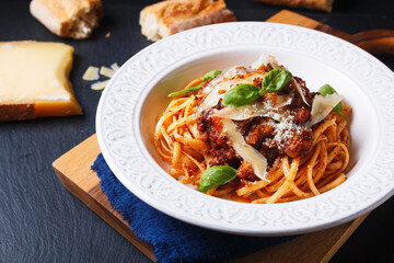 Food concept Homemade pasta Linguine meat bolognese sauce in a white ceramic pasta bowl on wooden board with black slate stone for copy space