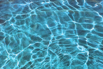 Marine background texture of sun glare through the water column reflected on the sandy seabed