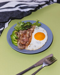 Healthy keto breakfast - bacon, fried eggs, avocado and microgreens. Low in carbohydrates, high in fat. Maintaining ketosis and boost ketone levels.
