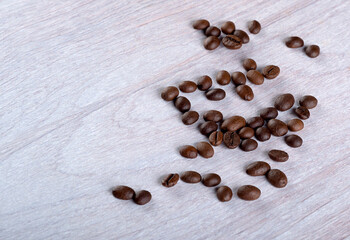 Coffee beans scattered on a light wooden background. Place for text