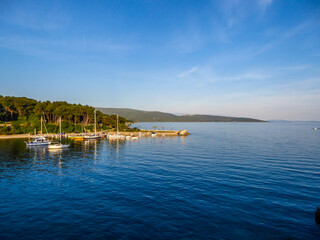 A view on pier in Krk, Croatia. Some yachts are anchored in the port. Endless horizon line, lots of island in the back. Clear and blue sky. Idyllic place.