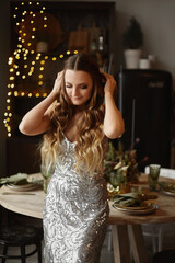 Amazing beauty young woman with trendy makeup in fashionable evening dress in the dining room decorated for Christmas dinner