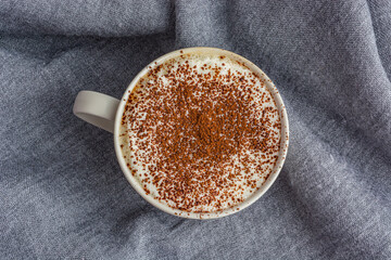 cup of coffee on gray fabric background top view