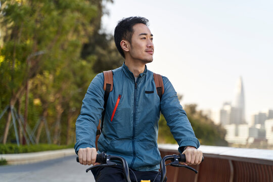 young asian man commuting by bike in modern city