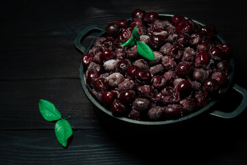 The studio shot of frozen cherry in a bowl on a wooden black background.Vitamins and a healthy diet