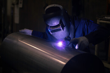 Welder is welding the steel in the factory. Weld the steel in dark. Workers wearing industrial...