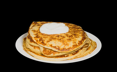 pancakes on a plate with sour cream isolated on black background
