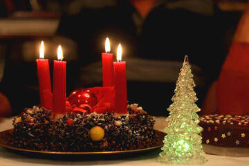 Advent wreath with four lit candles and Christmas decoration on a holiday table. Selective focus.
