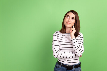 Photo of young attractive woman finger touch chin look empty space wondered isolated over green color background