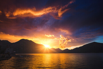 Bright red clouds illuminated by the sun, dark ominous sky.