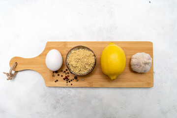 ingredients for mayonnaise: egg, lemon, garlic, mustard on the wooden. Grey background.