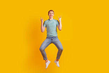 Fototapeta na wymiar Photo of young cheerful guy show fingers harsh metal brutal jump isolated over yellow color background