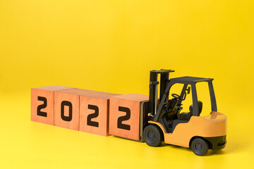 Happy new year 2022 industrial concept. new year background concept,  forklift carrying box wooden cubes to complete 2022 text.