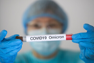 Woman in protective suit holding test tube with sample of analysis suspected to be infected with...