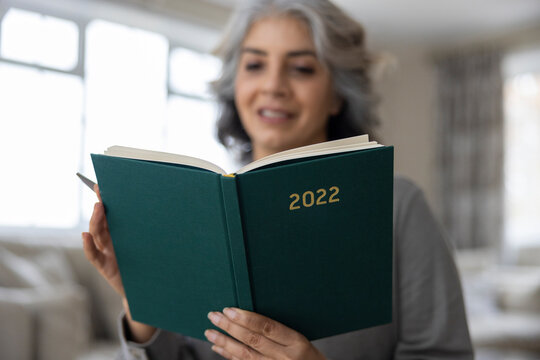 Close Up Of Mature Woman Holding New Year 2022 Diary At Home