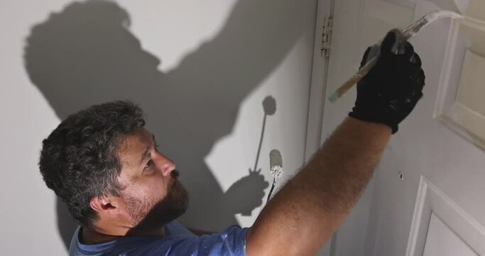 Hand of repairman painting with gloves in the painting door molding trim