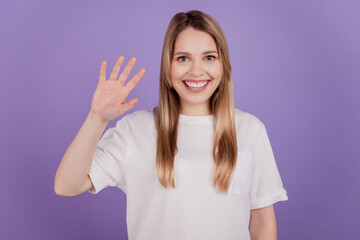 Photo of friendly nice lady cheerful mood wave hand wear casual t-shirt on violet background