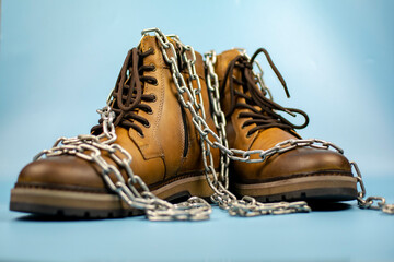 New pair of winter leather boots on a light blue background. Front view, decorated with a chain. Fashionable concept.