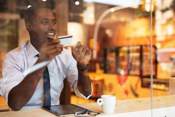 Businessman in cafe holding a credit card. Guy making online payment. Man paying the bill in cafe with a credit card.