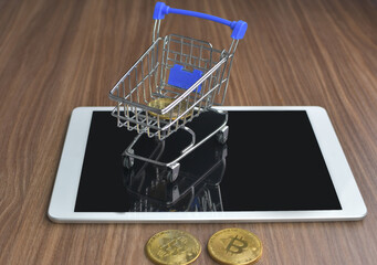 Fototapeta na wymiar Bitcoin is placed in the shopping cart placed on the tablet device in the concept of online shopping with credit card.